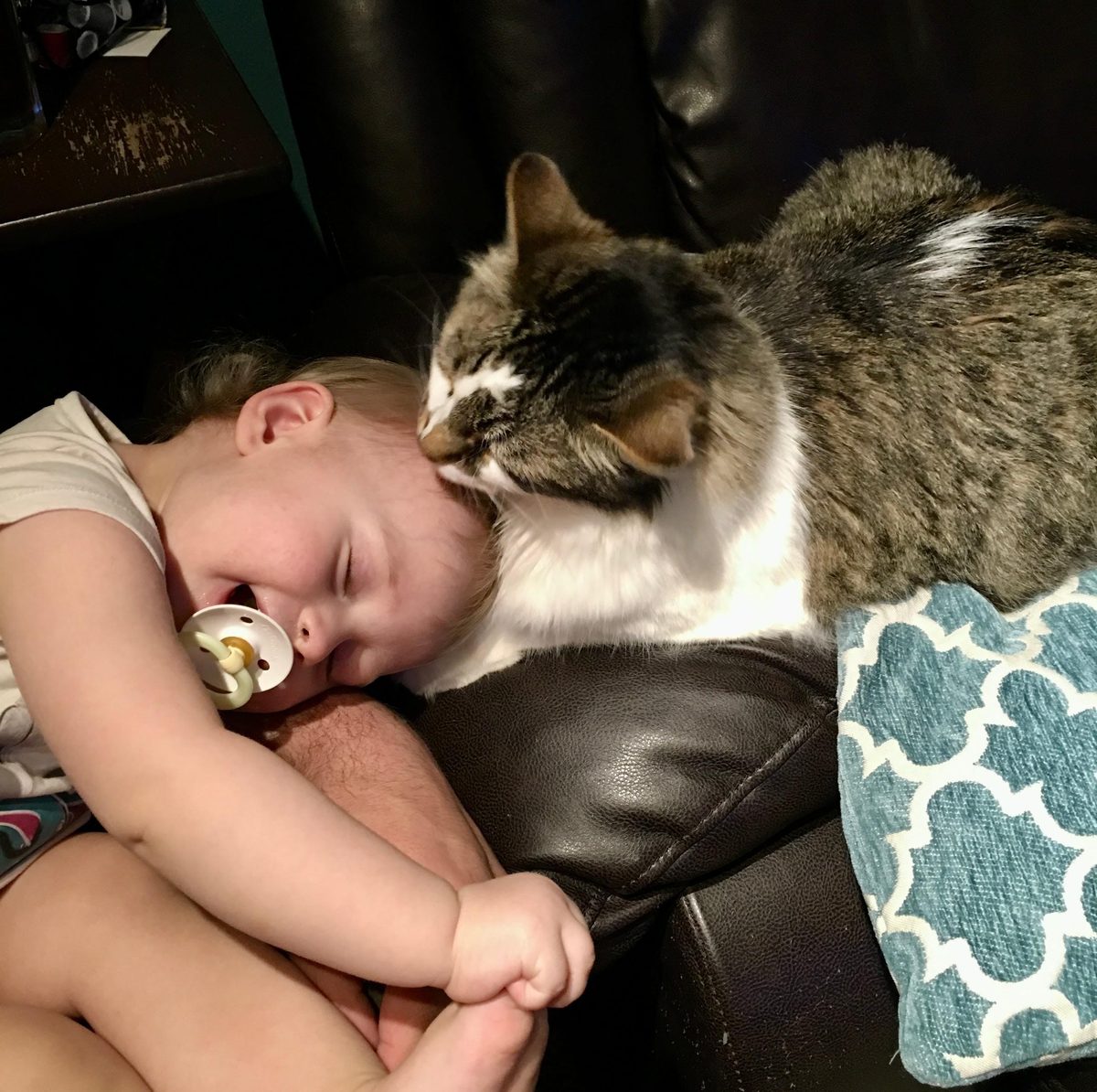 Sam asleep with his head resting on baby Addie, who is sleeping with a pacifier in her mouth.