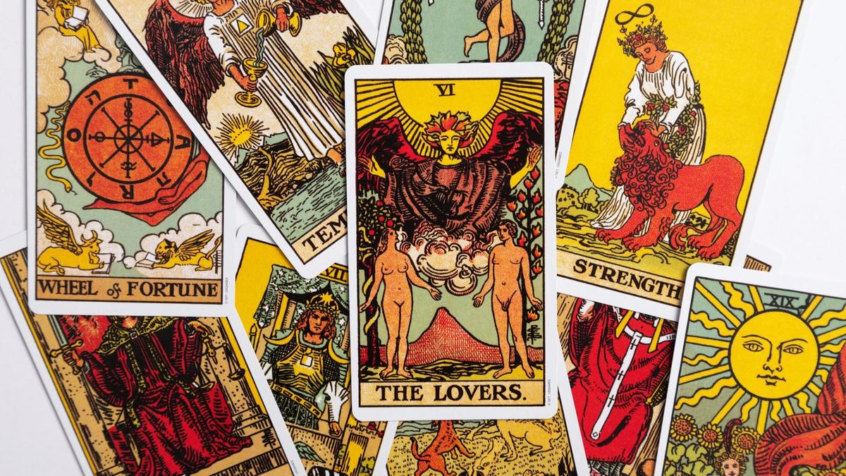Major Arcana tarot cards spread face-up, The Lovers in the centre, with Strength and the Wheel of Fortune beside it.