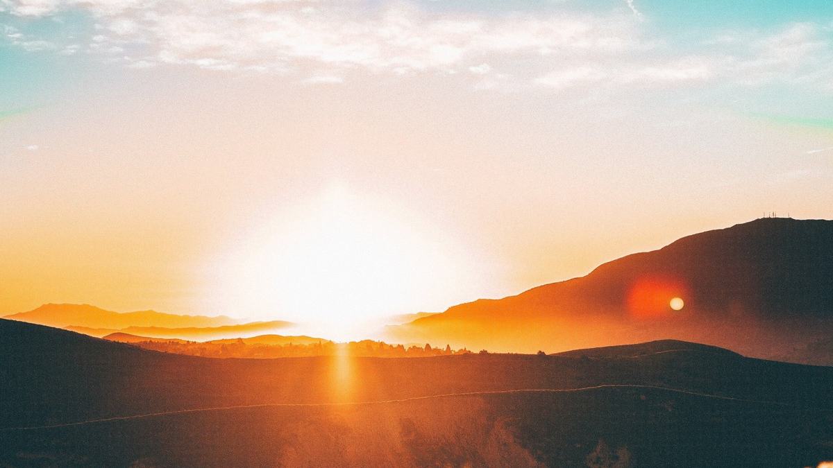 The sun rising over layered hills.