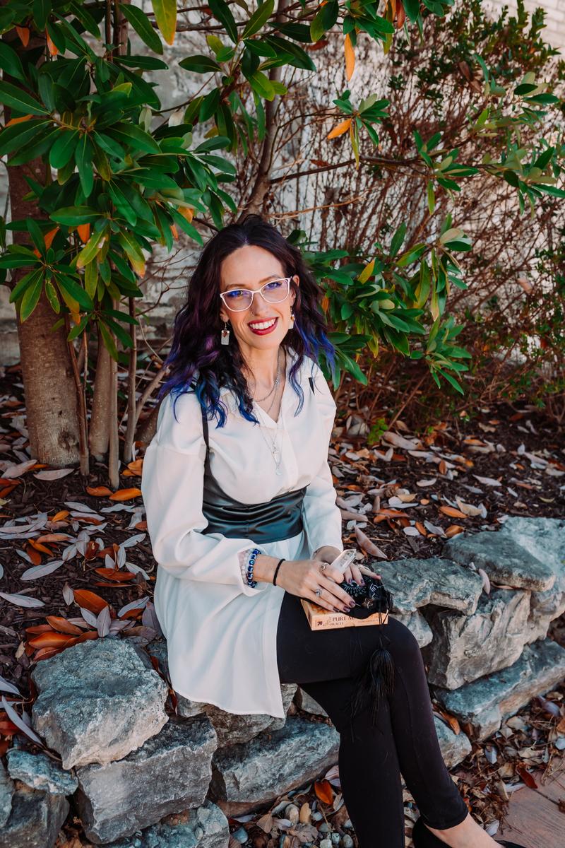 Angelita seated among magnolia leaves, holding a crystal